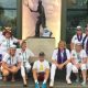 Geoff Hughes is sitting in the middle of a photo in front of a Fred Perry statue surrounded by members of the Andy Murray fan group The Murraynators