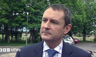 Matthew Wright is wearing a suit and looks serious as he is interviewed in a previous broadcast