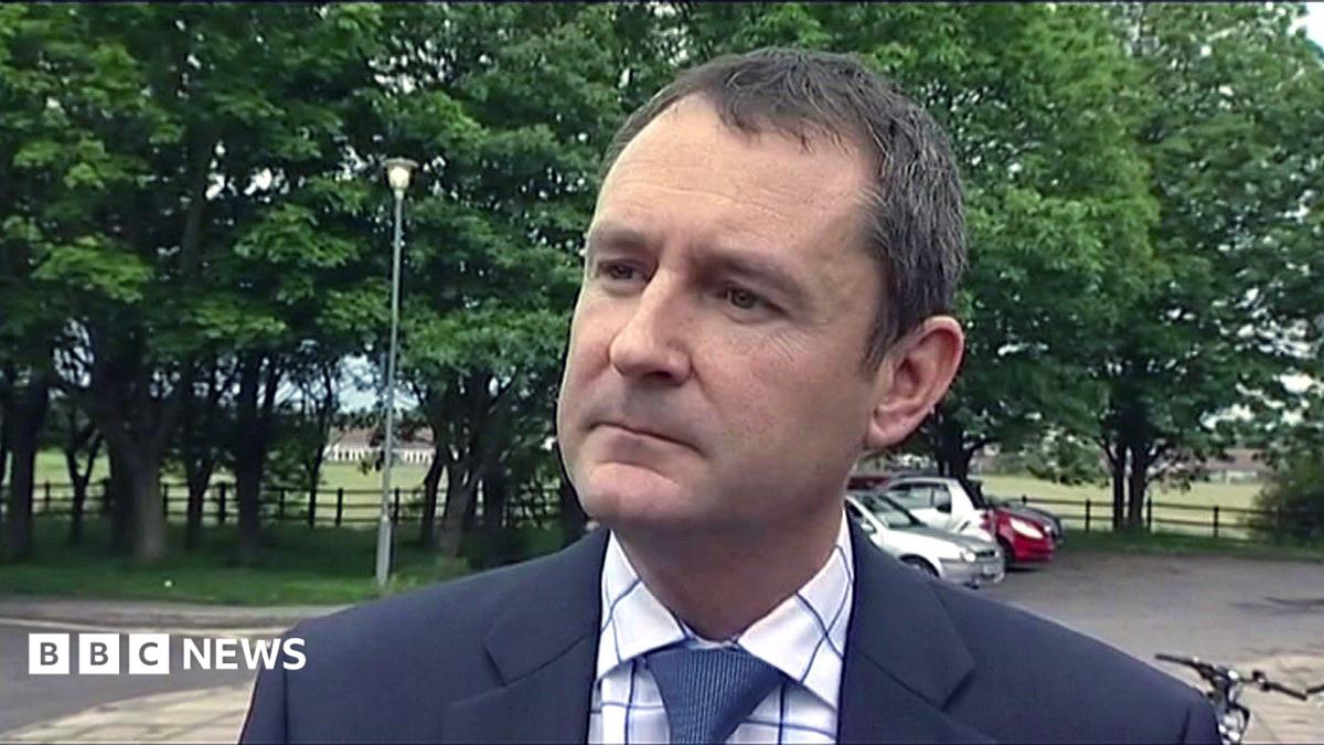 Matthew Wright is wearing a suit and looks serious as he is interviewed in a previous broadcast