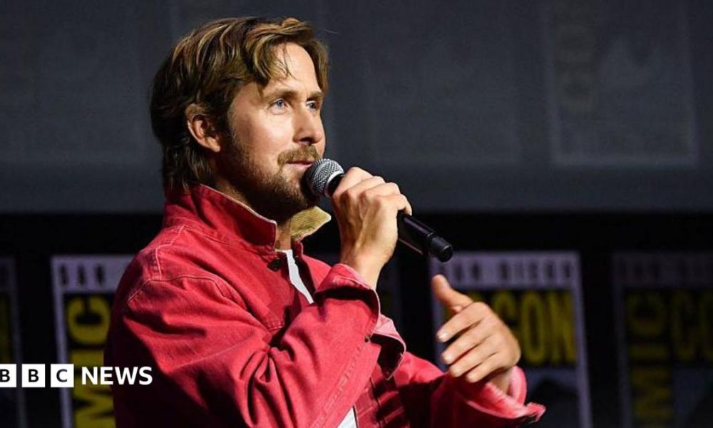 Ryan Gosling speaking into microphone on stage at San Diego Comic-Con