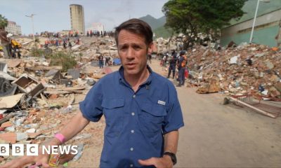 Man in blue shirt walking among rubble after earthquake