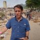 Man in blue shirt walking among rubble after earthquake