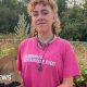 Alex Vardill wearing a pink T-shirt, smiling straight at the camera and holding a box of blackberries.