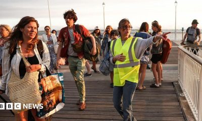 A volunteer gives indication to holidaymakers from Lege-Cap-Ferret upon their arrival in Arcachon by boat during an evacuation operation of the entire Cap-Ferret peninsula, in southwestern France, on July 24, 2026 whilst a wildfire is spreading across the area
