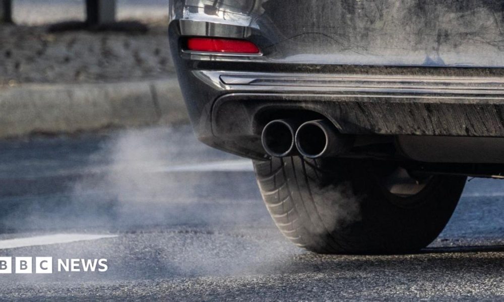 A car's exhaust pipe is in view with some of the car also shown.