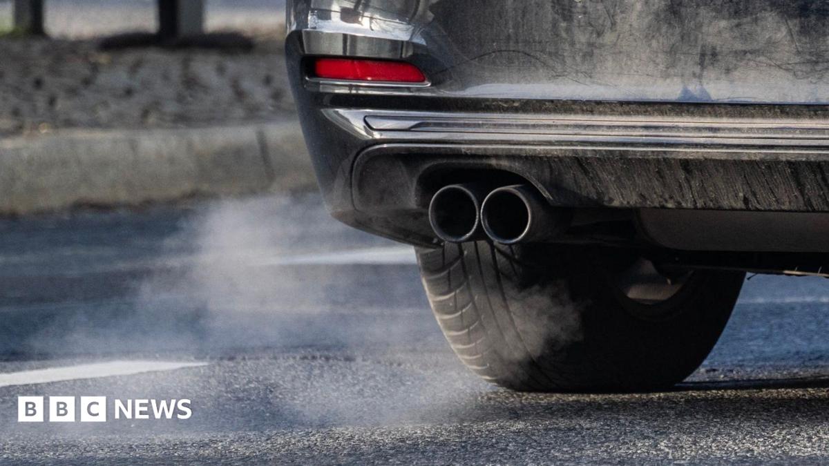 A car's exhaust pipe is in view with some of the car also shown.