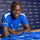 Quenda resting his arms on a table with a Chelsea shirt on and in front of him after signing for the club