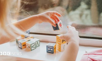 A child plays with letter blocks in front of a window