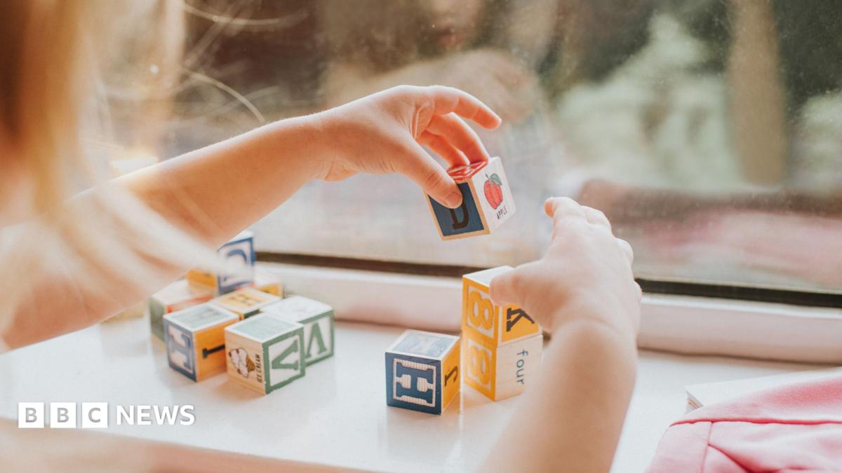 A child plays with letter blocks in front of a window