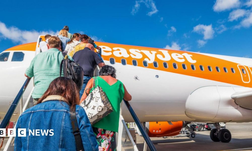 People climb the stairs onto an easyJet orange and white plane.