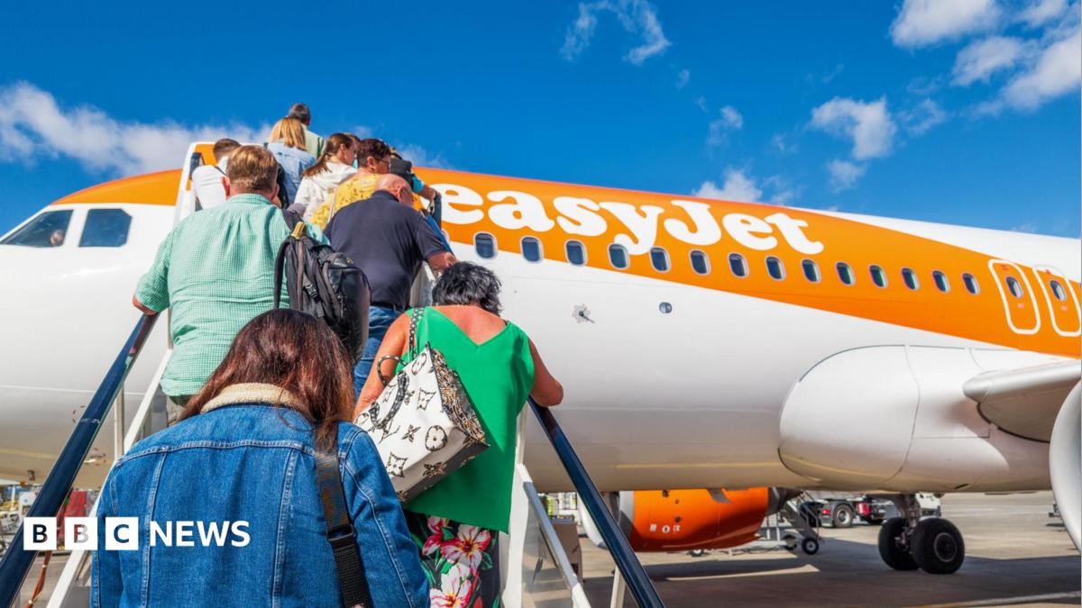 People climb the stairs onto an easyJet orange and white plane.