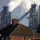 A British Steel plant, with steam billowing out of it, behind a row of terrace houses