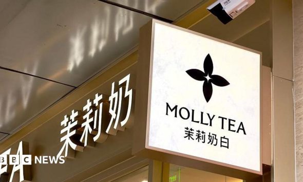 A view of Molly Tea's four-petal flower logo on a sign hanging on the sign of one of the brand's shops.