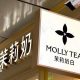 A view of Molly Tea's four-petal flower logo on a sign hanging on the sign of one of the brand's shops.