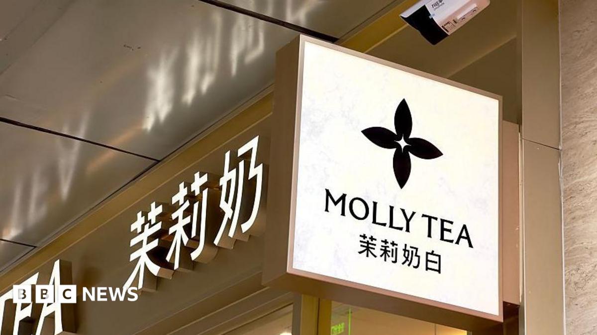 A view of Molly Tea's four-petal flower logo on a sign hanging on the sign of one of the brand's shops.