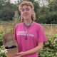 Alex Vardill wearing a pink T-shirt, smiling straight at the camera and holding a box of blackberries.