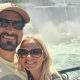 Man and woman wearing sunglasses smiling in front of a waterfall
