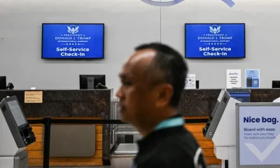 A traveler walks past new welcome signs reading "Donald J. Trump International Airport" on July 9, 2026.
