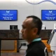 A traveler walks past new welcome signs reading "Donald J. Trump International Airport" on July 9, 2026.