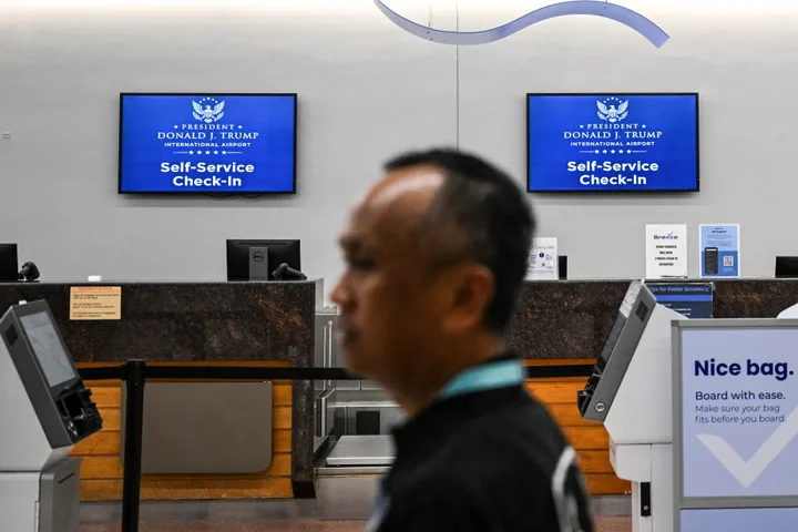 A traveler walks past new welcome signs reading "Donald J. Trump International Airport" on July 9, 2026.