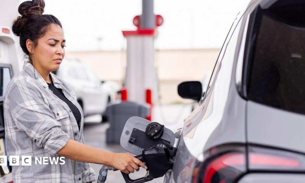Woman wearing a grey shirt fills up her car at a gas station
