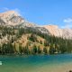 An aqua-blue river runs through a valley surrounded by pine trees and rocky mountains
