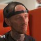 Steven, a man in a black t shirt and black snapback cap sat on a large orange chair.  He has a short red haired goatee.