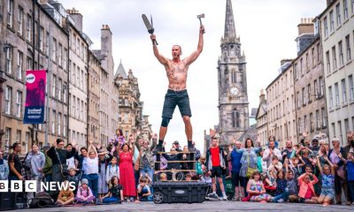 A bare-chested male street performer in front of a crowd on Edinburgh's Royal Mile.