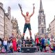 A bare-chested male street performer in front of a crowd on Edinburgh's Royal Mile.