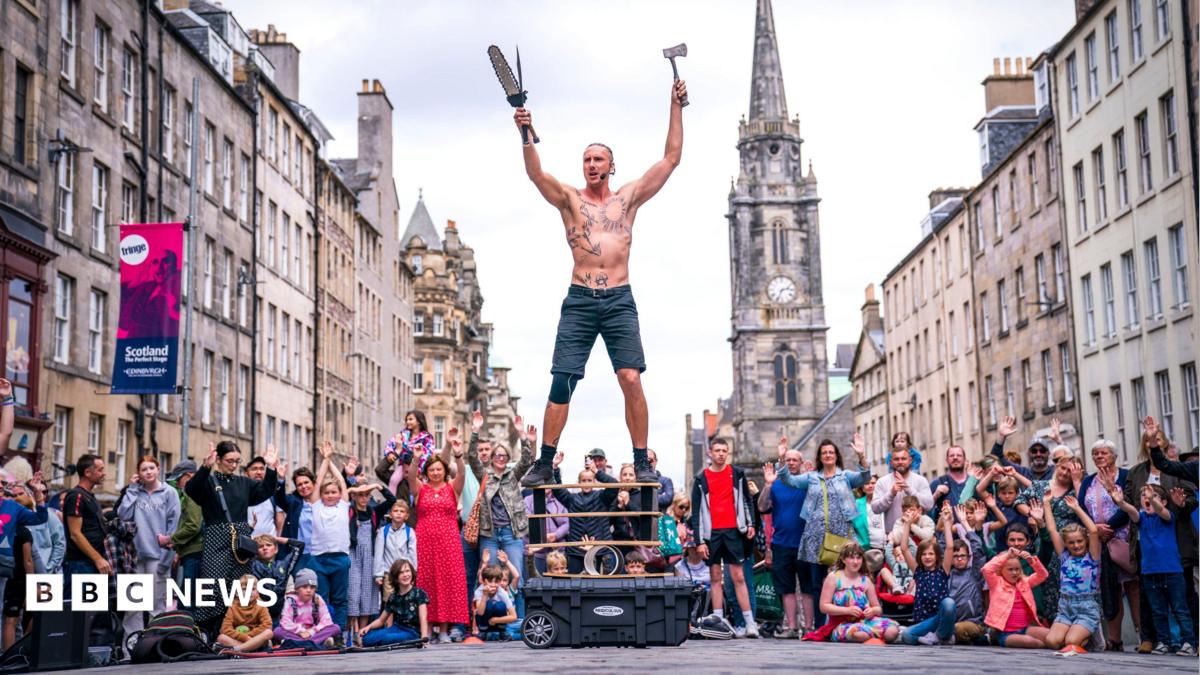 A bare-chested male street performer in front of a crowd on Edinburgh's Royal Mile.