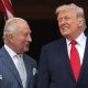 King Charles looking at Donald Trump, both wearing suits and smiling.
