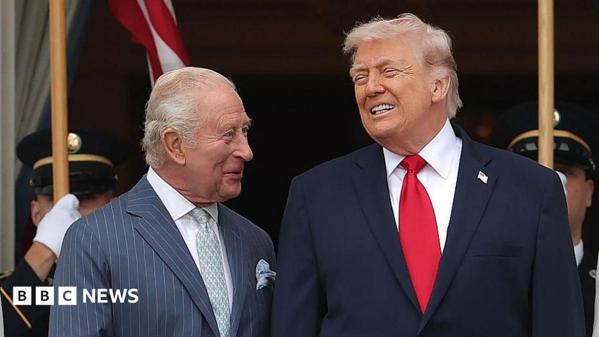 King Charles looking at Donald Trump, both wearing suits and smiling.