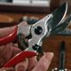 Close up of a pair of left-handed secateurs with red handles.