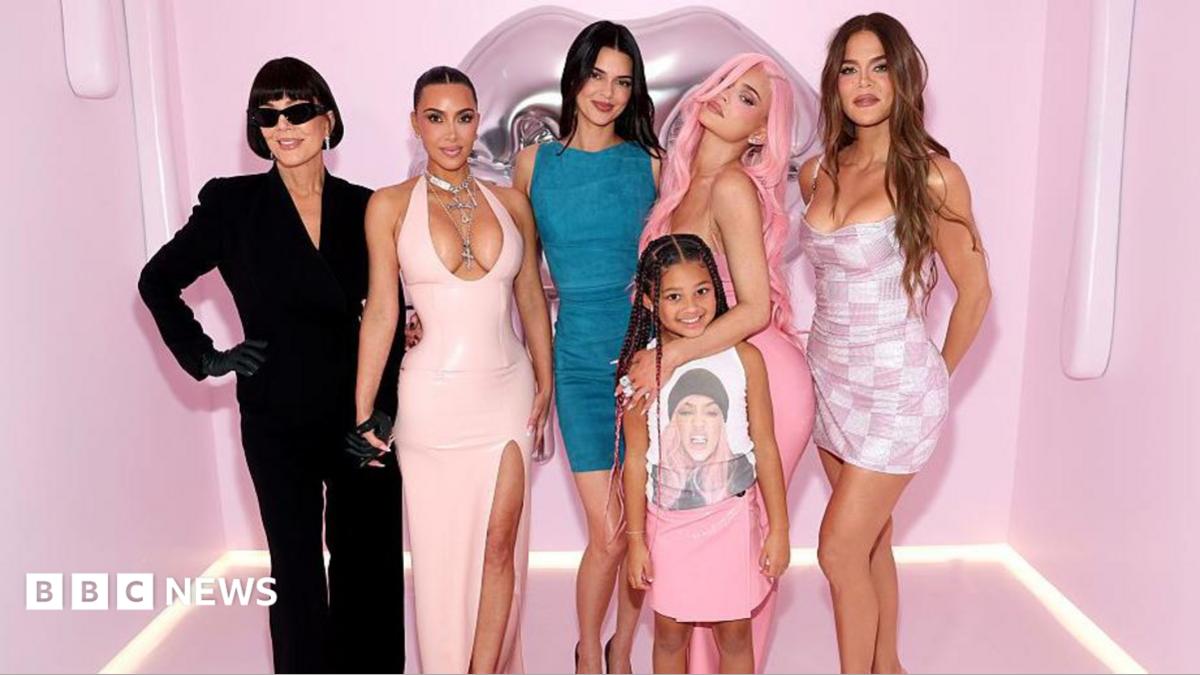 The Kardashian family is pictured posing in front of a pink background