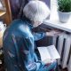 A stock image of an elderly woman holding an energy bill while sat close to a radiator.