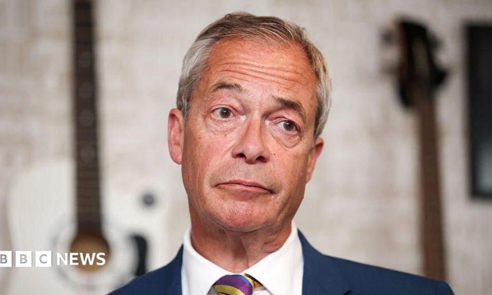 Nigel Farage in a close-up, wearing a blue suit, white shirt and stripe tie.