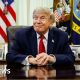 US President Donald Trump smiles while sitting at the Resolute Desk