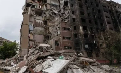 A concrete tower block in Ukraine damaged from an air strike from Russia with scorch marks on the side and rubble piled up on the ground