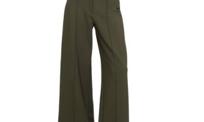 A woman (torso cropped out) wearing a white top, ivory vest, and wide-leg olive pants