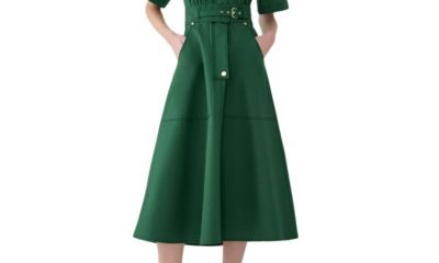 A woman (head cropped out) wearing a green belted dress and dark bronze heels