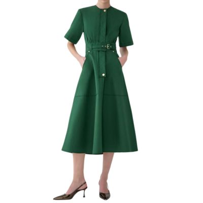 A woman (head cropped out) wearing a green belted dress and dark bronze heels