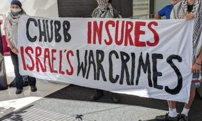 Chubb lobby protesters lod a banner saying Chubb Insures Israel's War Crimes
