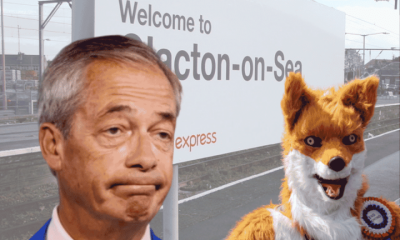 An image of Clacton-On-Sea's railway track with the sign in show. In front of them on the right is Rob Pownall dressed in his red fox outfit. On the left is an image of Nigel Farage's bust, and he is looking perplexed