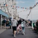 A bustling scene at Llandudno promenade in Wales with people walking near a Ferris wheel adorned with flags. Days out like this will not be affordable for many UK families due to money worries.