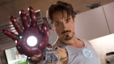 Robert Downey Jr as Tony Stark holding up robotic hand in Iron Man (2008)
