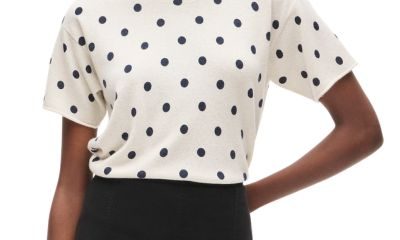 A woman wearing and ivory-and-navy polka dot top and black shorts
