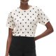 A woman wearing and ivory-and-navy polka dot top and black shorts

