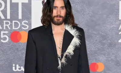 Jared Leto in a suit blazer with his bare chest exposed at the top, posing infront of Brit Award backdrop. Year unknown.