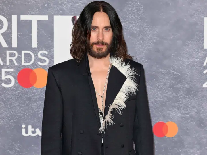 Jared Leto in a suit blazer with his bare chest exposed at the top, posing infront of Brit Award backdrop. Year unknown.