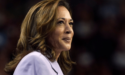 Kamala Harris smiling with a closed mouth in a smart suit looking into the distance, looking relaxed and assured